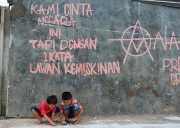 Sebuah tulisan ditembok rumah warga di Desa Karet, Kecamatan Sepatan, Kabupaten Tangerang " KAMI CINTA NEGARA INI TAPI DENGAN 1 KATA LAWAN KEMISKINAN" sementara dua bocah asik bermain disana ( Ragawilapa)